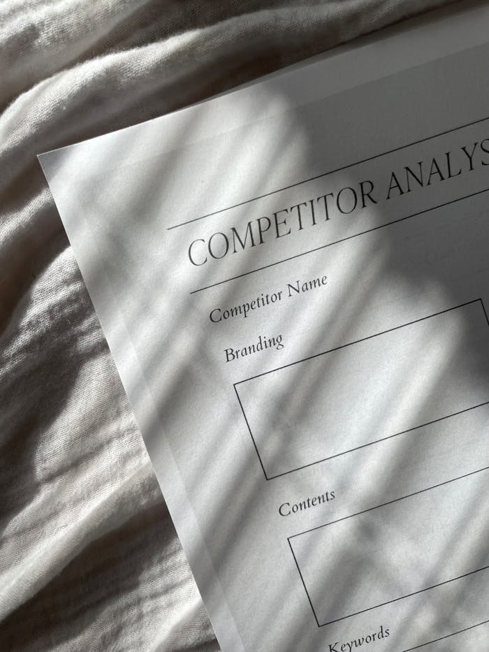 about-us-02 A competitor analysis sheet with stylish shadows on a textured fabric background, conveying a professional tone.
